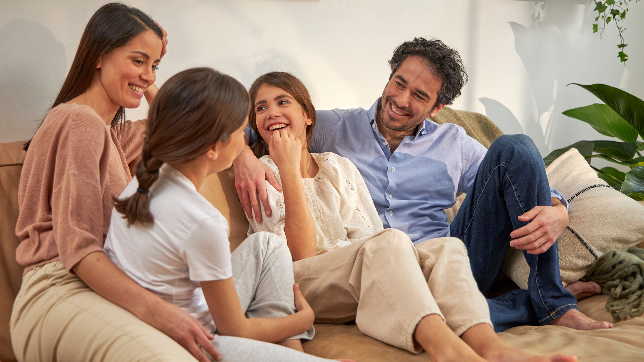 En familie sidder i sofaen og taler sammen.